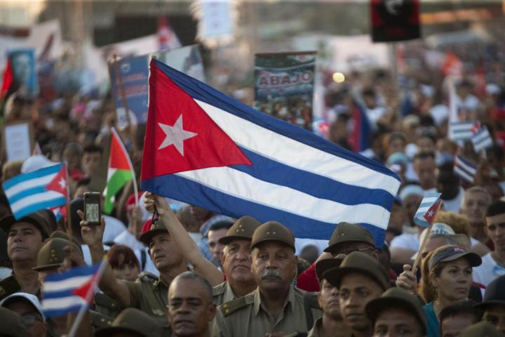 Miles de cubanos enarbolan su bandera nacional, entre militares del ejército revolucionario, en la marcha del Primero de Mayo de 2024, en La Habana.