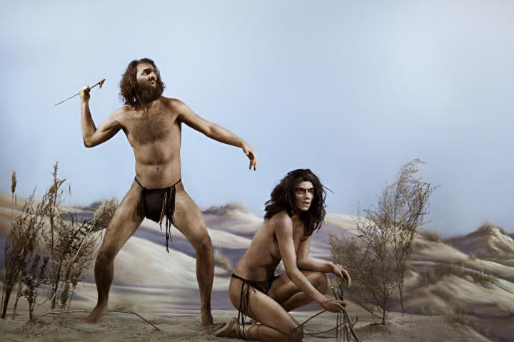 Un hombre prehistórico junto a una mujer arrodillada.