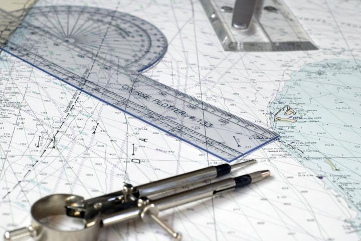 Low depth of field image of chart plotter, parallel rules and divider on a chart.