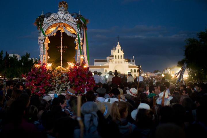 SANLUCAR DE BARRAMEDA, SPAIN - MAY 17: Pilgrims walk behind the carriage carrying the Simpecado of the Hermandad del Rocio de Huelva with La Ermita del Rocio in site after a two day journey from Huelva on May 17, 2013 in El Rocio, Spain. The Romeria del Rocio procession brings together roughly a million pilgrims each year making their way for as long as seven days from throughout Andalusia by foot, on horsebacks and horse drawn carriages, to the doors of the Hermitage of El Rocio. On Sunday night, after reciting the Holy Rosary at candlelight, and the passing of all the simpecados in front of the chapel, with the one from the brotherhood of Matriz de Almonte as the last one, el salto de la reja begins, the jumping of the fence surrounding the Hermitage after which the Virgin of El Rocio is carried out onto the sandy streets of the small town for the 'Blanca Paloma' procession. Then, the long camino home begins. Dating back from 1653, it was in 1758, when the Virgin of Las Rocinas became known as the Virgin of El Rocio, that the pilgrimage started to take place in the weekend of the Sunday of Pentecost, 50 days after Easter Sunday. (Photo by Jasper Juinen/Getty Images)