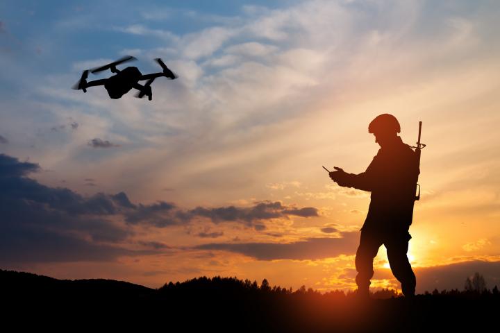 Fotomontaje de un soldado en sombras maniobrando con un dron.