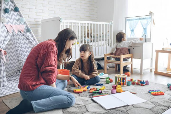 Una madre y sus dos hijas jugando en la habitación de los niños.