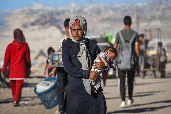 Una mujer palestina carga a su bebé mientras huye del norte de la franja tras los intensos ataques israelíes, en la ciudad de Gaza, el 1 de octubre de 2025.