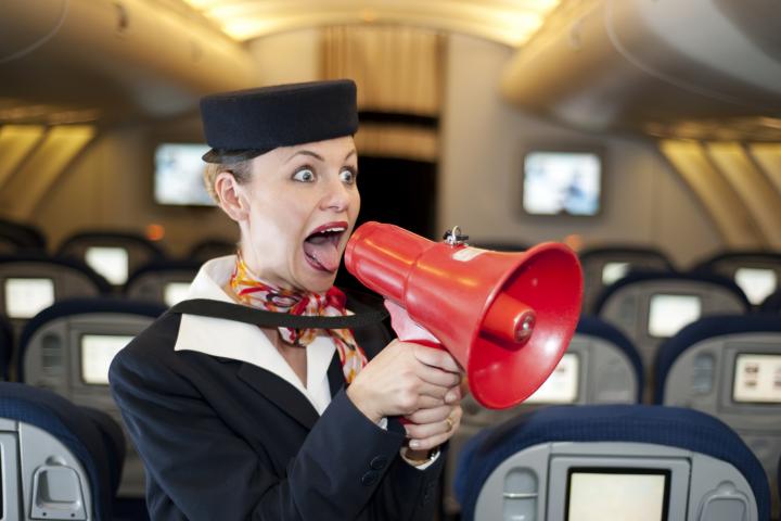Azafata en un avión con un megáfono
