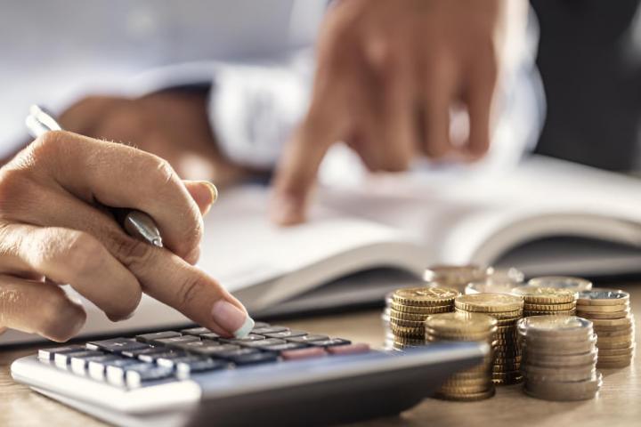 Un hombre y una mujer calculan los gastos del presupuesto familiar con ayuda de una calculadora.