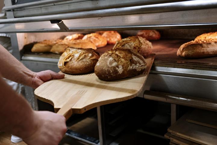 Un panadero sacando pan recién horneado del horno en una panadería