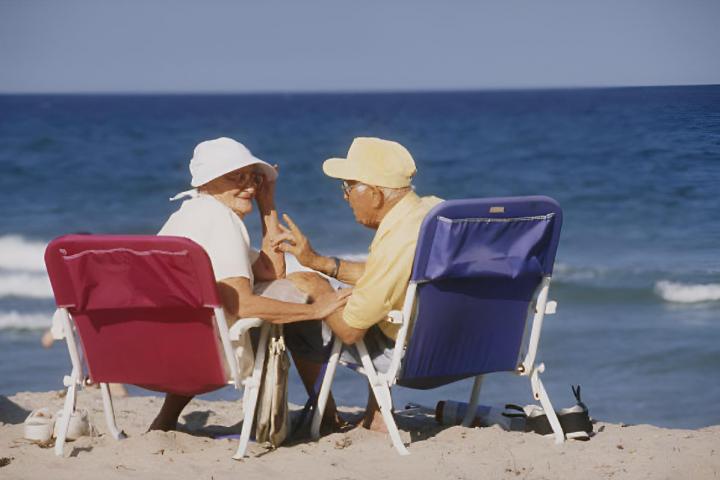 Una pareja de ancianos sentados en unas sillas plegables a la orilla de mar