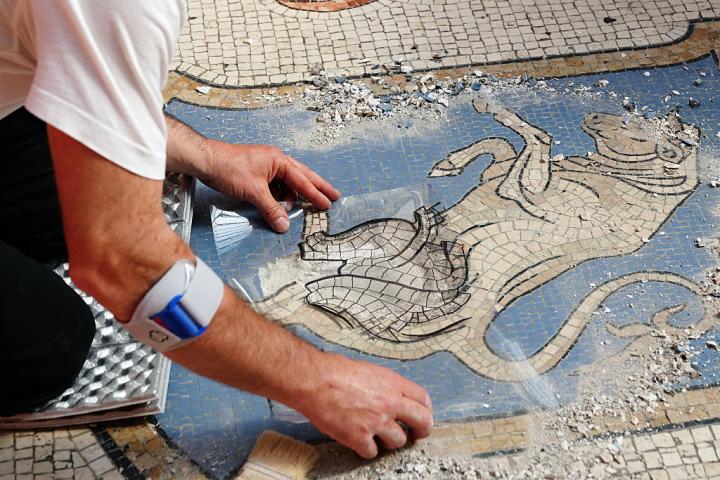 Un trabajador restaurando el mosaico del toro de la Galería de Víctor Manuel II, en Milán (Italia)