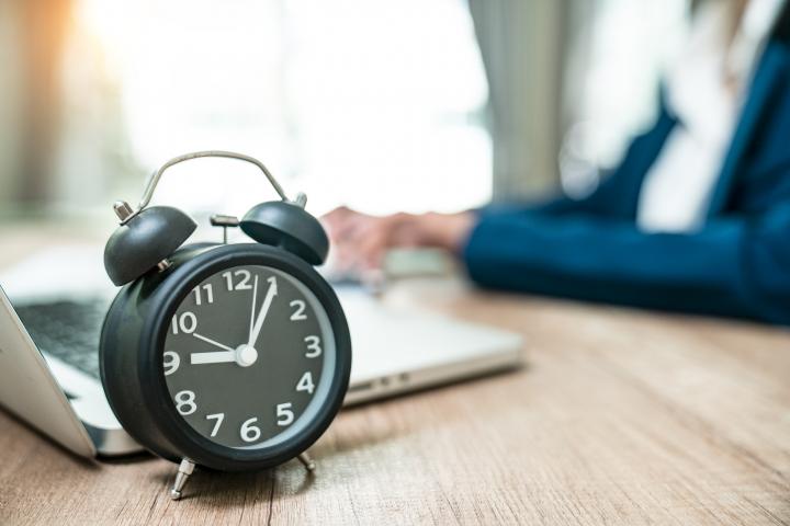 Un reloj junto a una trabajadora