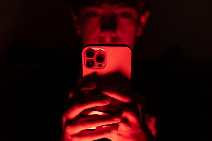 Imagen de un menor consultando su teléfono móvil a oscuras.