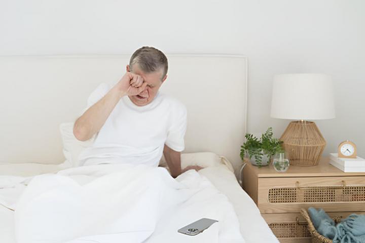 Una persona mayor recién despertado en la cama.