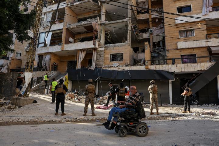 Un hombre en silla de ruedas pasa junto a personal de emergencia que trabaja en el lugar donde se produjo un ataque de Israel, en un suburbio del sur de Beirut, el 7 de junio de 2026.