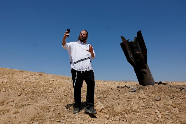 Un israelí ultraortodoxo posa ante los restos de un misil iraní, en el West Bank, en la Cisjordania ocupada por Israel.