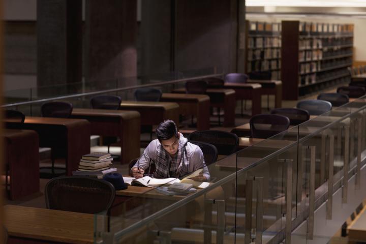 Un joven estudiando en una biblioteca, en una imagen de archivo