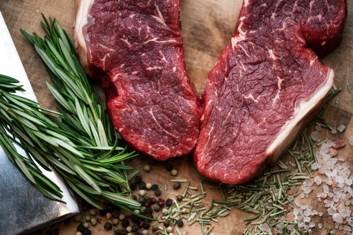 Filete de ternera madurada en seco de primera calidad con hierbas aromáticas sobre una mesa de madera.