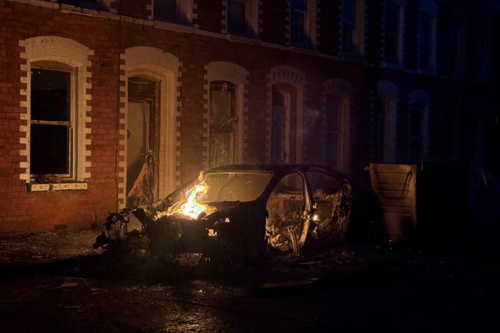 Un coche arde en el este de Belfast, durante una protesta tras un ataque con cuchillo ocurrido el 8 de junio de 2026 que dejó a un hombre gravemente herido.