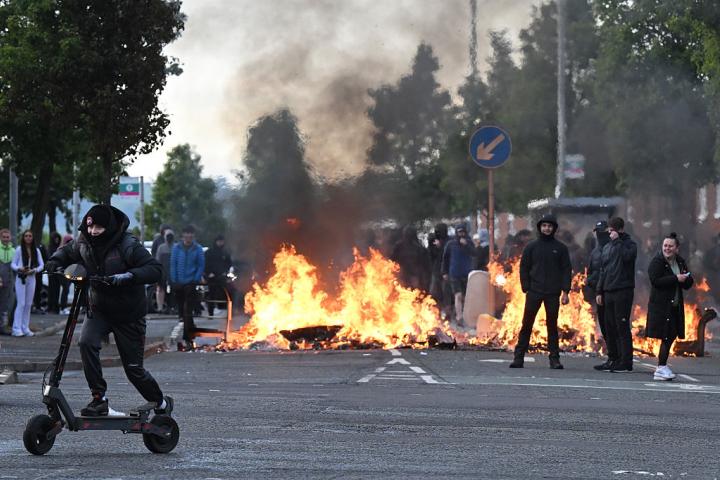Un grupo de jóvenes se congrega frente a una barricada en llamas en Duncairn Gardens, el 9 de junio de 2026, en Belfast (Irlanda del Norte), en mitad de una ola de ataques racistas.
