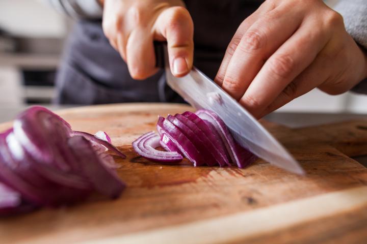 Una persona cortando cebolla morada