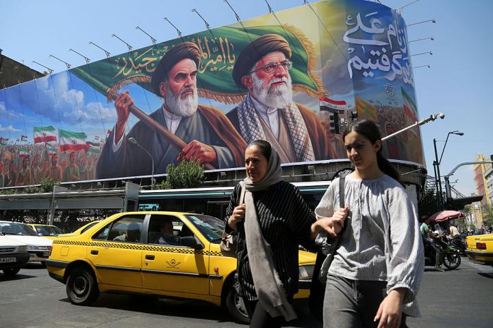 Unas mujeres pasan ante un cartel con los rostros de Ruhollah Jomeini y Ali Jamenei, los antiguos líderes supremos de Irán, el 8 de junio de 2026, en Teherán.