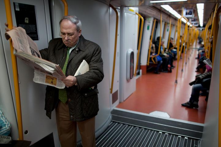 Un hombre lee el periódico en el Metro de Madrid