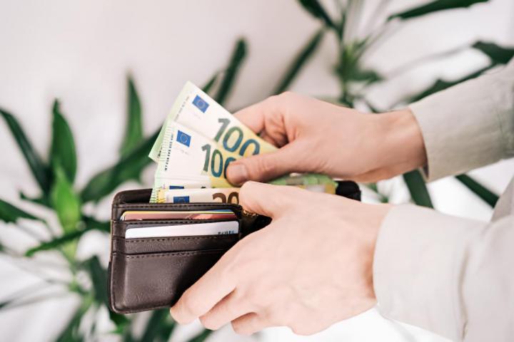 Un hombre sacando billetes de 100 euros de una cartera