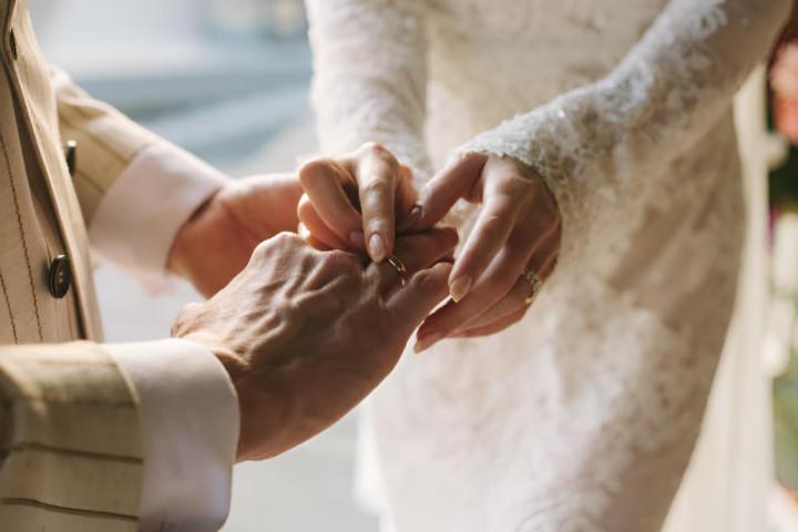 Una novia colocando el anillo en el dedo al novio en una boda
