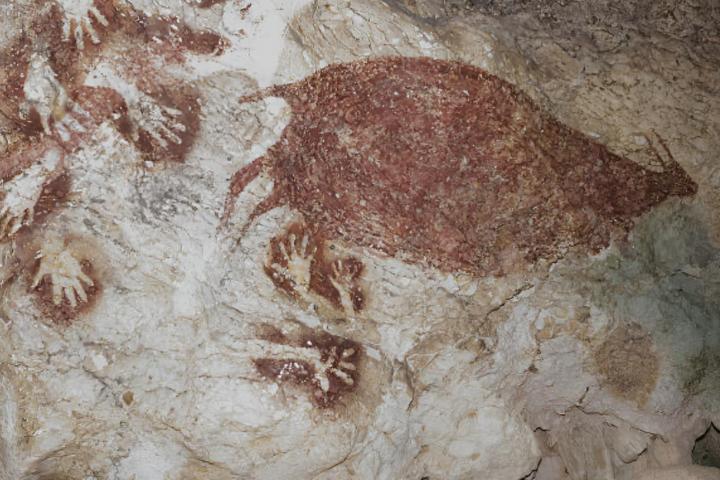 Ciervos rojos salvajes y plantillas de manos en pinturas rupestres prehistóricas de la cueva Sumpang Bita