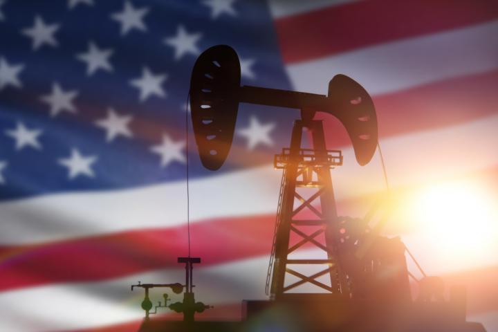 Ilustración de una planta petrolera, con la bandera de EEUU al fondo.