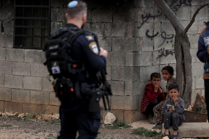 Un policía israelí, ante varios niños palestinos en el West Bank, tras varios ataques de colonos.