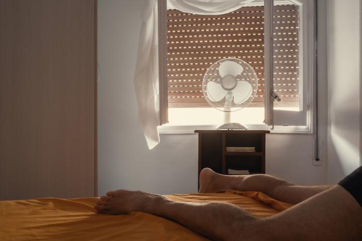 Imagen de una persona sufriendo una ola de calor en la habitación de una vivienda.