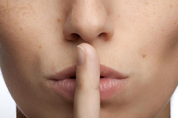 Una mujer poniendose un dedo en los labios haciendo el gesto de silencio