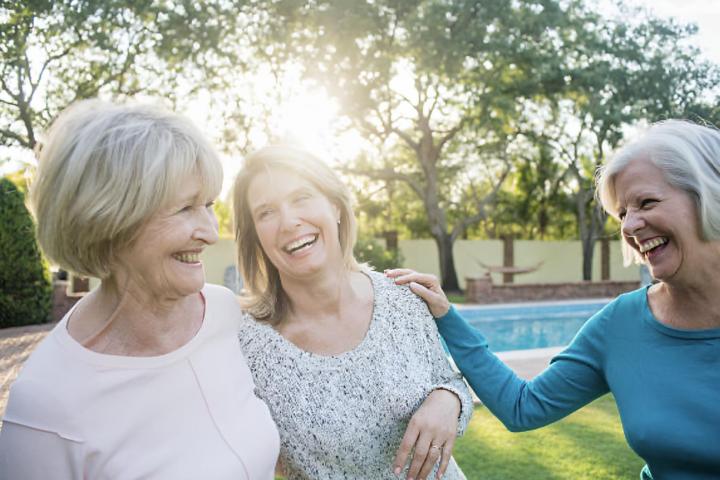 Tres mujeres mayores riéndose en un jardín