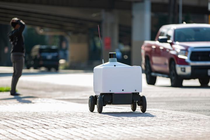 Un robot de reparto autónomo impulsado por inteligencia artificial recorre una acera en Dallas, Texas.