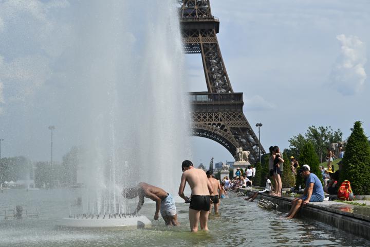 Parisinos se refrescan en las fuentes cerca de los Jardines del Trocadero, con la torre Eiffel al fondo en París.