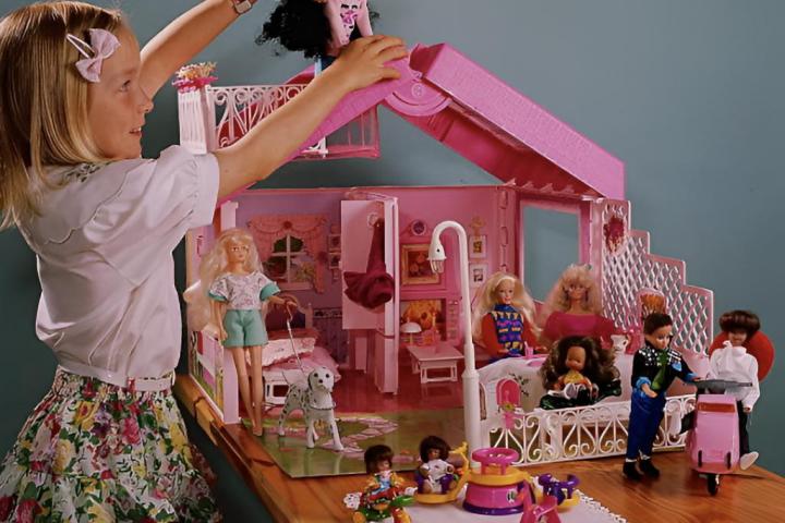 Una niña pequeña jugando con una casa de muñecas de Barbie
