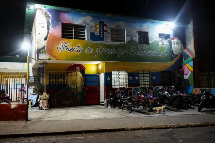 La gente descansa en la calle, junto a un edificio con los rostros de Simón Bolívar y Hugo Chávez, por temor a regresar a los edificios dañados por los terremotos, el 25 de junio de 2026, en Caracas.