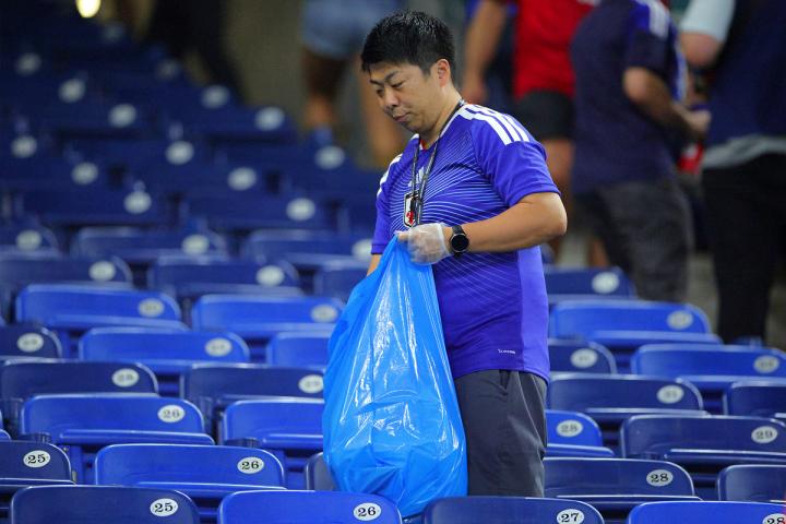 Un aficionado japonés recogiendo basura con su bolsa azul tras un partido del Mundial 2026