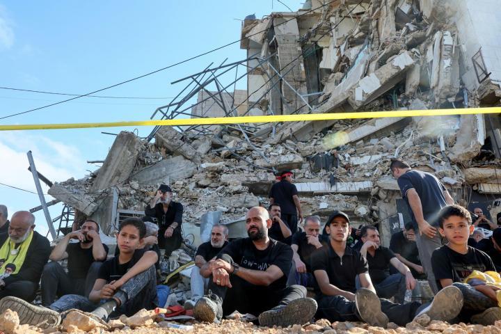 Partidarios de Hezbolá escuchan la historia participan en un acto por el Día de Ashura, frente a un edificio destruido en el sur de Beirut (Líbano), el 26 de junio de 2026.