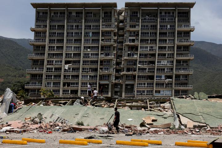 Un grupo de personas inspeccionan los escombros de un edificio dañado tras los terremotos que azotaron el país, en La Guaira (Venezuela), el 25 de junio de 2026.