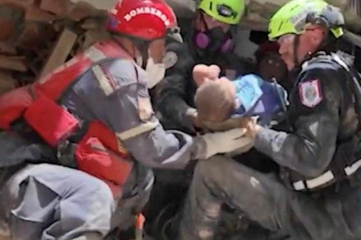 Captura de un vídeo publicado el 27 de junio de 2026, en la que se ve a trabajadores de emergencia transportando a un bebé rescatado de entre los escombros tras los terremotos en La Guaira (Venezuela).