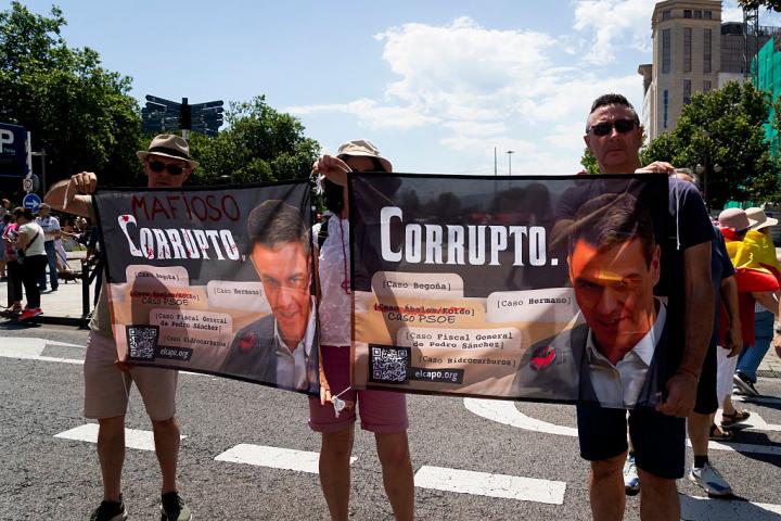 Dos personas portan un cartel en el que se puede leer "Sánchez corrupto"