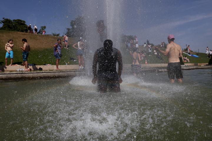 La gente se refresca en las fuentes del Trocadero, junto a la Torre Eiffel, durante la ola de calor que azota París (Francia), el 27 de junio de 2026.