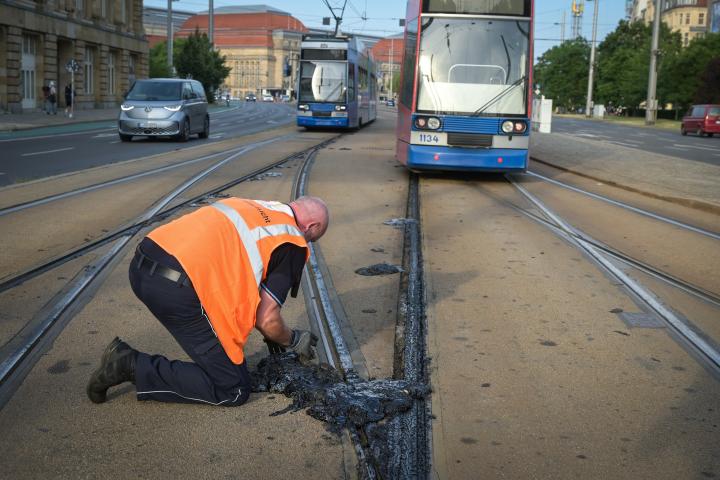 Un operario se afana en retirar el material sellante de la red de tranvía que se ha derretido por la ola de calor en Leizpig, Alemania, durante junio de 2026