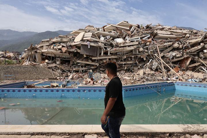 Una persona camina entre los escombros de edificios demolidos mientras continúan las labores de rescate tras el terremoto de Venezuela, el 25 de junio de 2026, en La Guaira.
