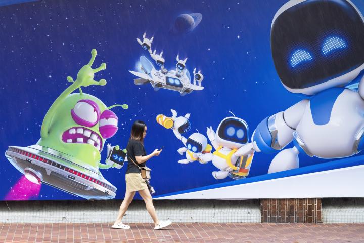 Una mujer pasea junto al mural de Astrobot, la mascota de PlayStation 5