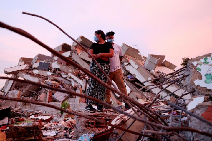 Yohancy Gil y Sergio Guanipa, de pie sobre los escombros mientras esperan noticias de los equipos de rescate que buscan a sus hijos en La Guaira (Venezuela), el 30 de junio de 2026.