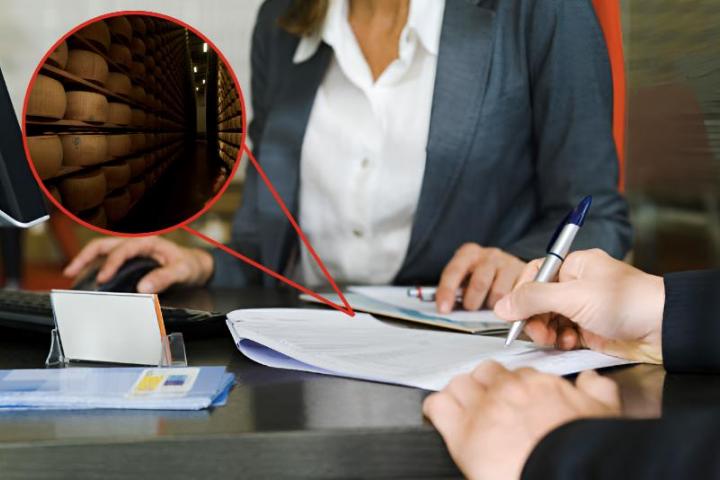 Una imagen de archivo de una persona firmando documentos en un banco y otra de un almacén de ruedas de queso.