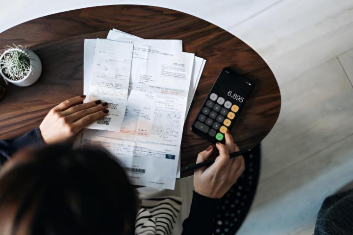 Una mujer organizando sus facturas y calculando cuánto tiene que pagar
