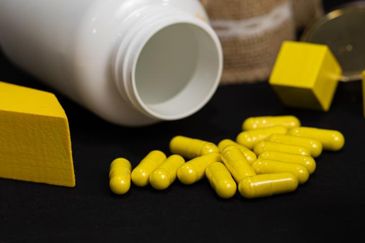 Frasco blanco de suplementos con cápsulas amarillas