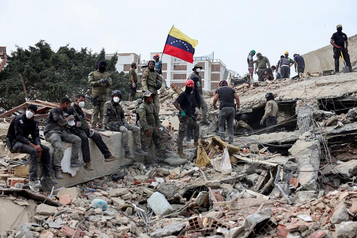 Los equipos de rescate colocan una bandera de Venezuela sobre los escombros, tras el doble terremoto sufrido por el país, el 28 de junio de 2026, en Caracas.